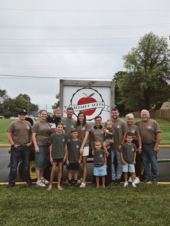 kids and adults gathered around a wagon with a hillside acres sign smiling